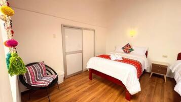 Une chambre à coucher comprenant un lit, une chaise, une table de chevet et une lampe fixée au mur.