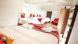 Une chambre d’hôtel avec un grand lit, deux petits lits et une armoire.