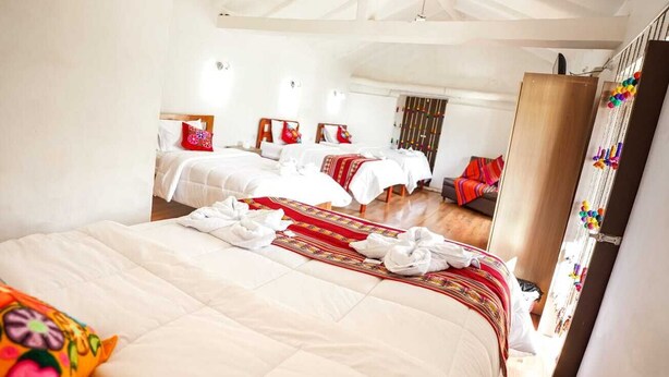 A hotel room with a large bed, two smaller beds, and a wardrobe. - Horizonte Hotels (Cusco)