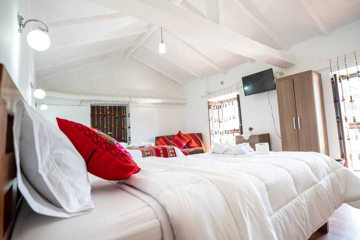 A bedroom with a large bed, a wardrobe, a television, and a window with colorful decorations.