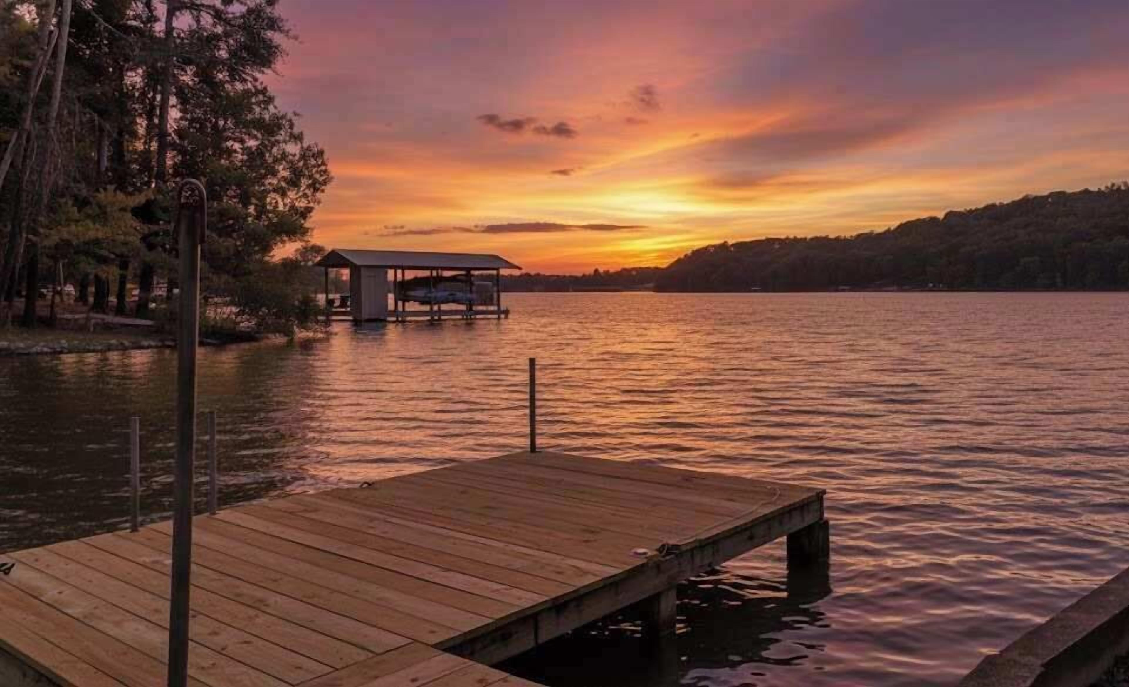 A wooden dock extending into calm water with a small cabin on stilts in the background.