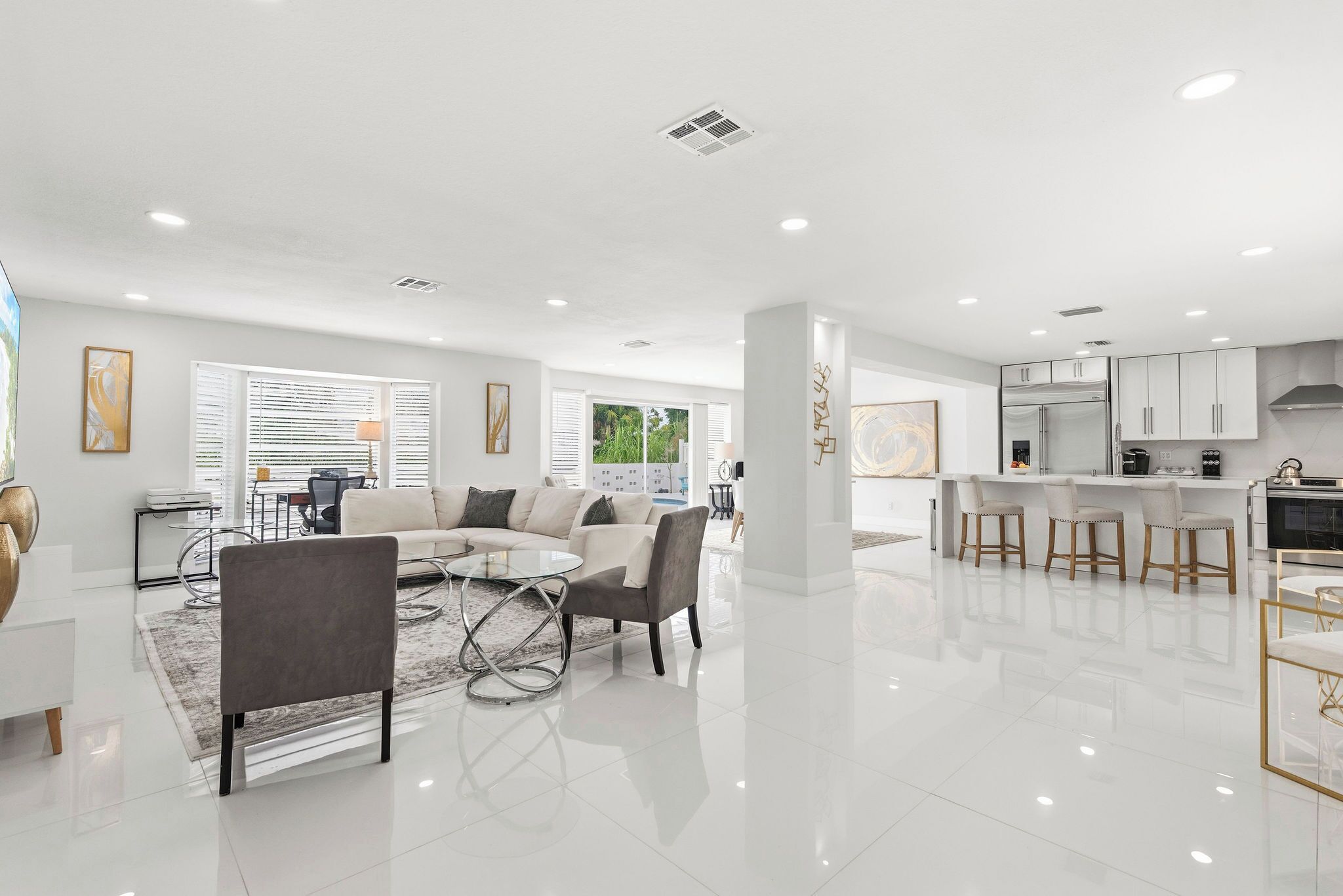 A modern living room with a sofa, chairs, a coffee table, and a dining area with a bar.