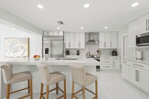 A modern kitchen with white cabinetry, stainless steel appliances, and a marble countertop. - Charming 3BR/2BA Pool Home in Sarasota, Total Comfort, Minutes to Siesta Key! (Sarasota)