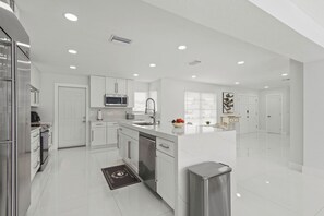 A modern kitchen with white cabinetry, a stainless steel refrigerator, a microwave, and a dishwasher. - Charming 3BR/2BA Pool Home in Sarasota, Total Comfort, Minutes to Siesta Key! (Sarasota)