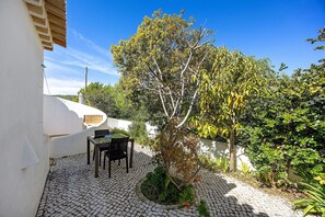 A courtyard with a tiled floor, a small tree, and a table with chairs.
