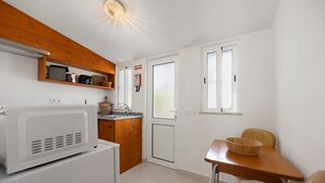 A compact kitchen with a microwave, wooden cabinets, a sink, and a dining area with a table and chairs.
