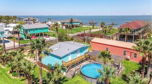 Zona residencial con piscina rodeada de palmeras y casas.