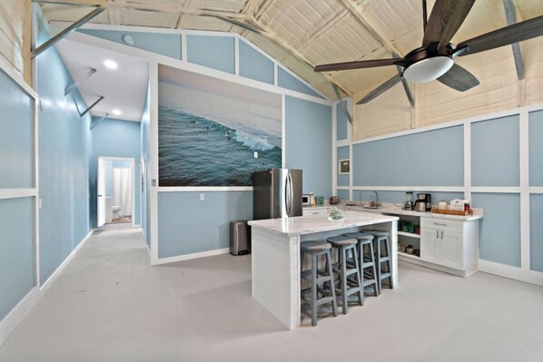 Una cocina moderna con una isla central, taburetes de bar y un ventilador de techo.
