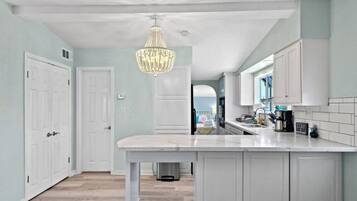 A kitchen with white cabinetry, a marble countertop, and a chandelier.