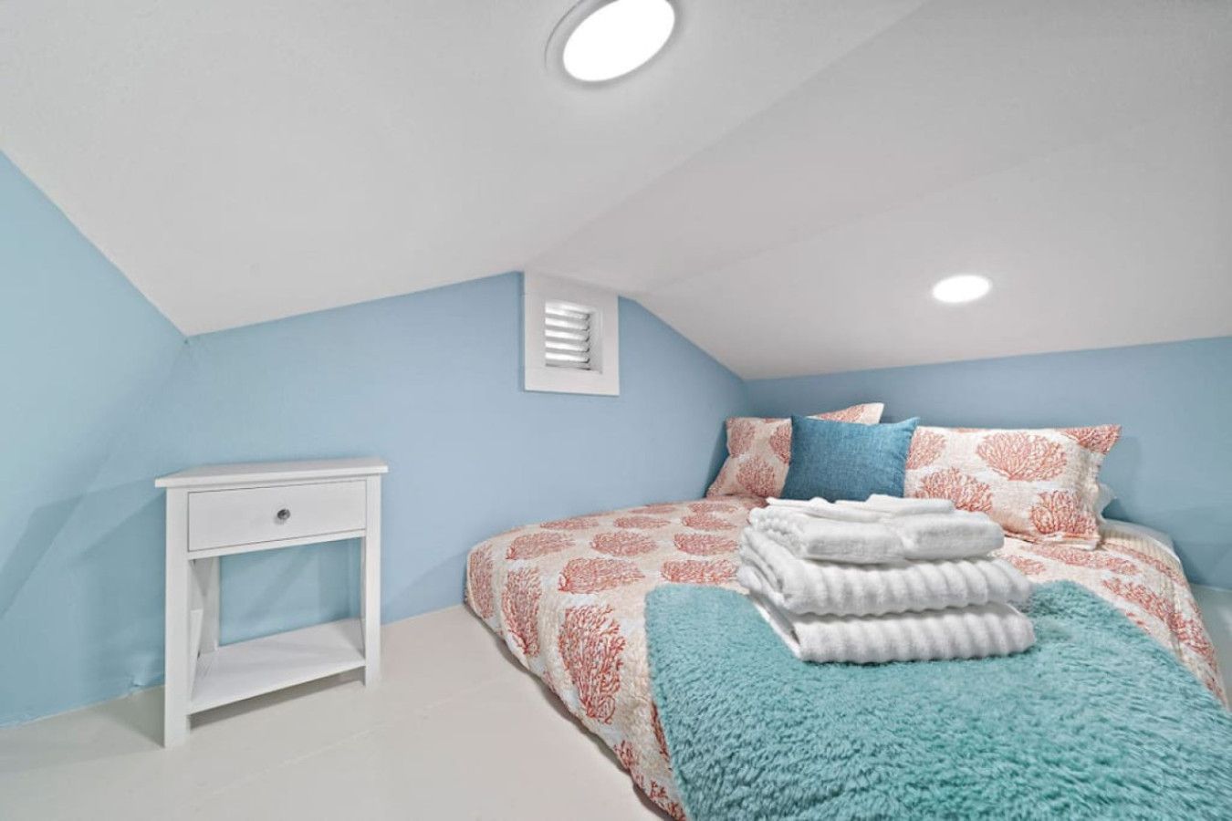 Un dormitorio con cama, mesita de noche y ventana con persianas.