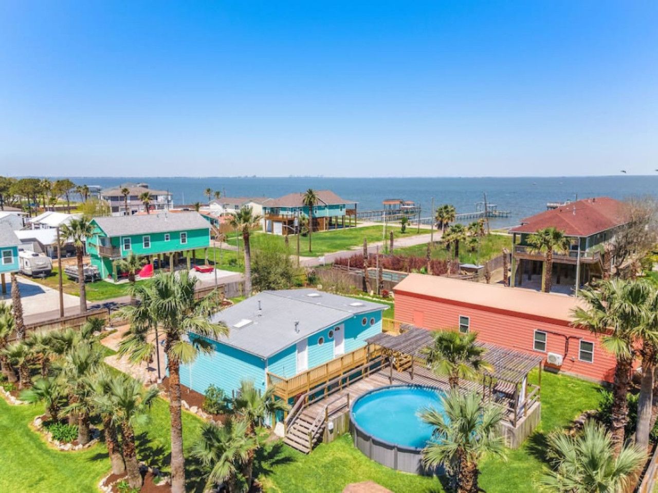 Zona residencial con una amplia piscina, varias casas y vistas al océano.