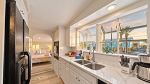 A modern kitchen with a large window, a sink, and a coffee maker. - Family-Friendly Retreat with Pool & Outdoor Lounge (Kemah Area)