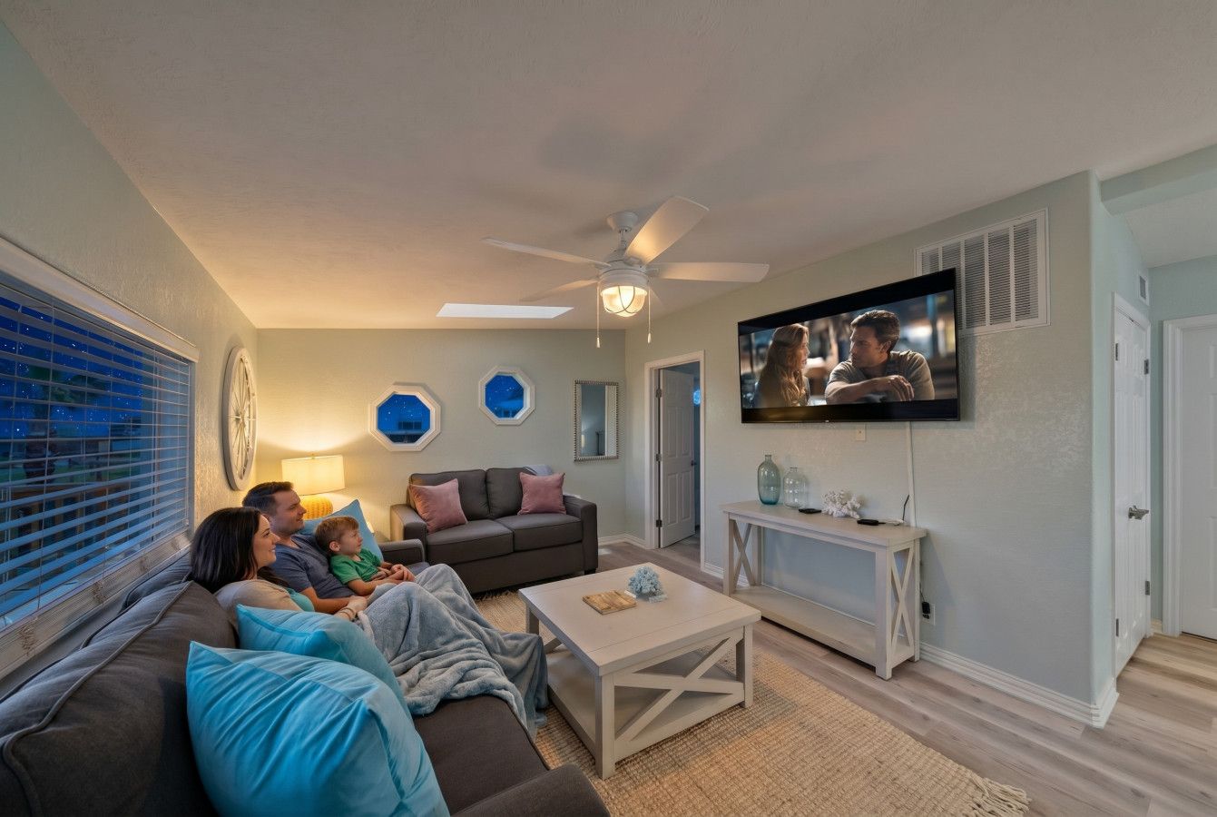 Una sala de estar con sofá, mesa de centro, televisor y ventilador de techo.