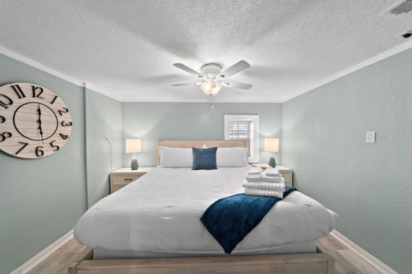 Un dormitorio con una cama grande, un ventilador de techo y un reloj de pared.