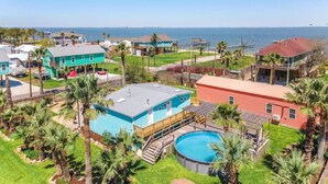 A residential area with a large swimming pool, multiple houses, and a view of the ocean. - Family-Friendly Retreat with Pool & Outdoor Lounge (Kemah Area)
