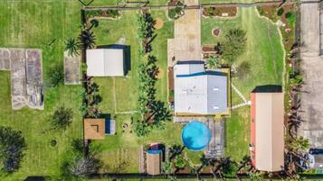 An aerial view of a residential area with a large house, a swimming pool, and several smaller structures.