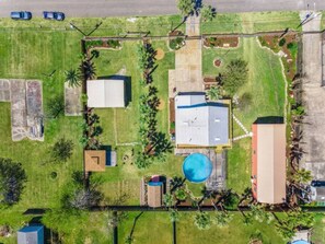 Vista aérea de una zona residencial con una casa grande, una piscina y varias construcciones más pequeñas.