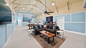 A spacious living area with a pool table, a sofa, and a ceiling fan. - Family-Friendly Retreat with Pool & Outdoor Lounge (Kemah Area)