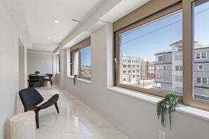 Eine moderne Wohnung mit großen Fenstern, einem Essbereich und einem Flur, der zu einem weiteren Raum führt.