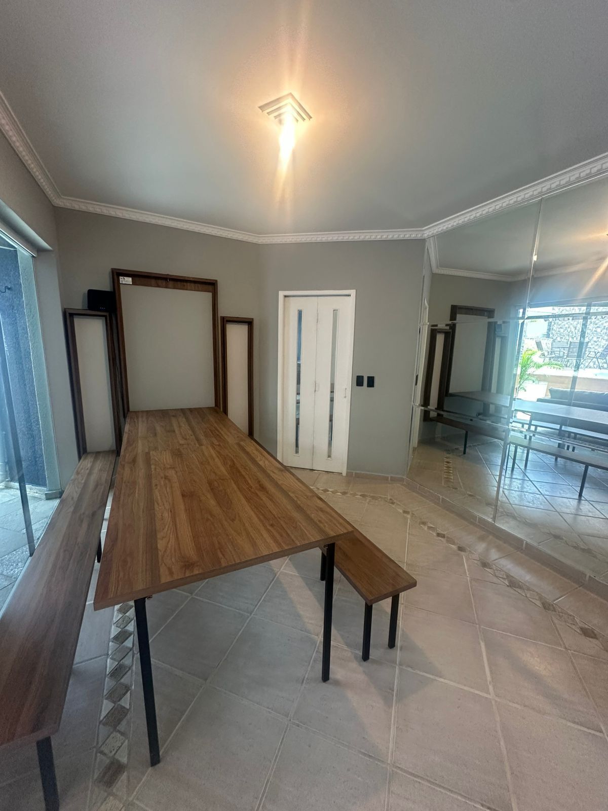 A spacious room with a large wooden table, a bench, and a door.
