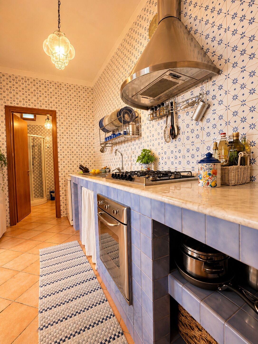 Una cocina con estufa, horno y ollas colgadas.