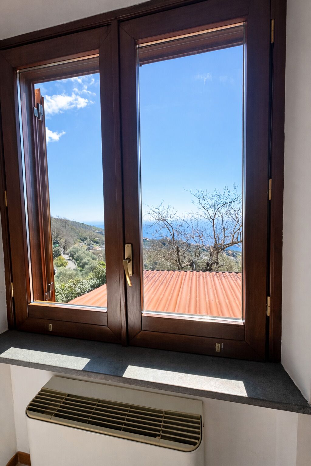 Ein Zimmer mit Blick auf eine gebirgige Landschaft durch ein Fenster mit Holzrahmen.