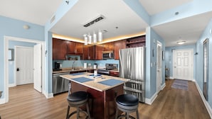 A modern kitchen with a central island, stainless steel appliances, and wooden cabinets. - Dolphin Views! Laketown Wharf - 7th Floor! (Panama City Beach)