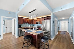 A modern kitchen with a central island, stainless steel appliances, and wooden cabinets. - Dolphin Views! Laketown Wharf - 7th Floor! (Panama City Beach)