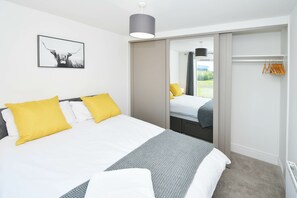 Quarto de hotel com cama, espelho, guarda-roupa e janela.