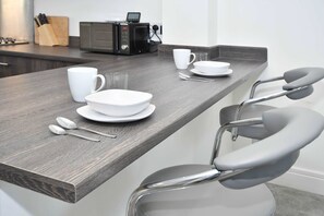Eine moderne Küche mit dunkler Holz Arbeitsplatte, einer Mikrowelle und einer Kaffeemaschine.
