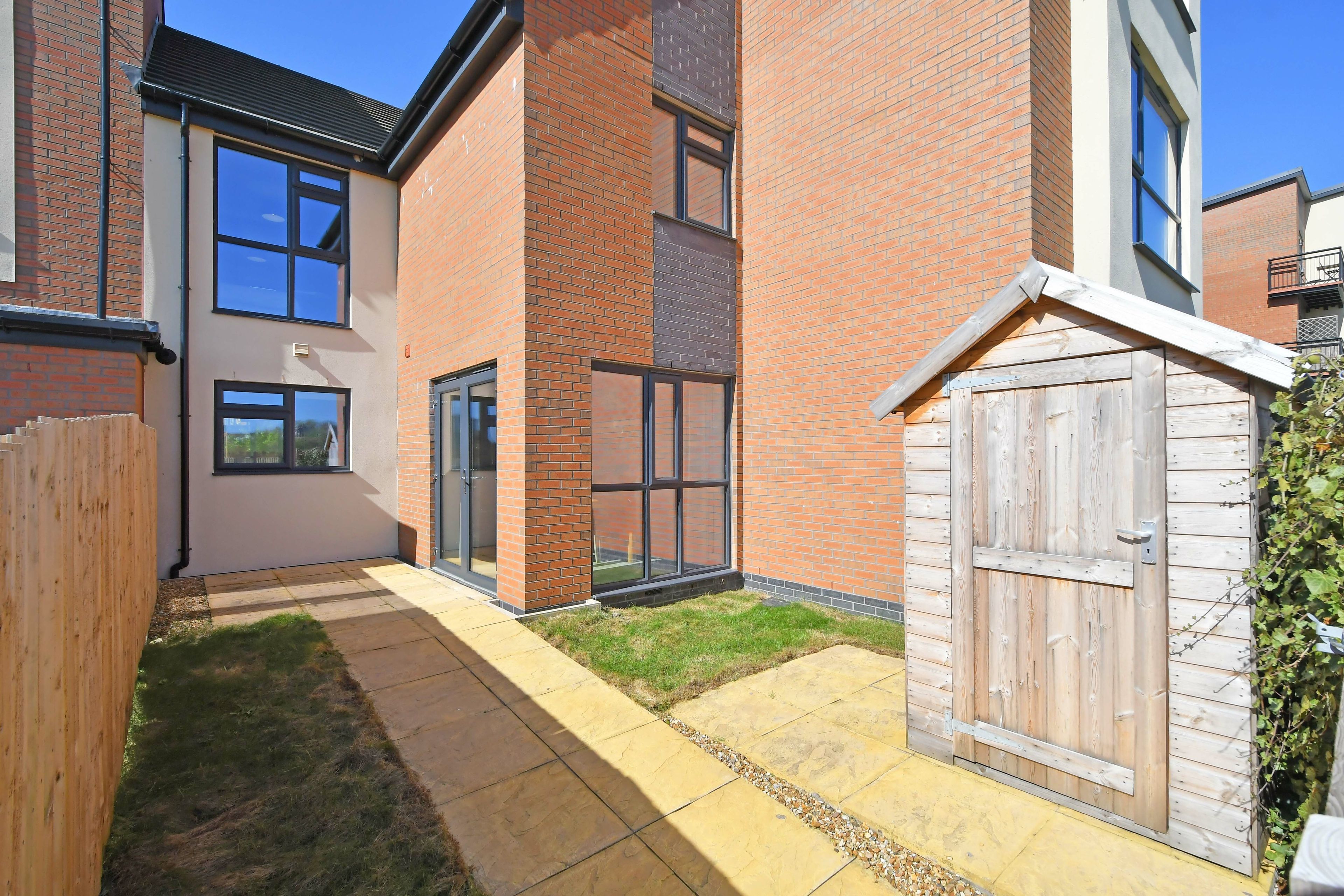 A modern building with a brick facade, large windows, and a wooden gate.