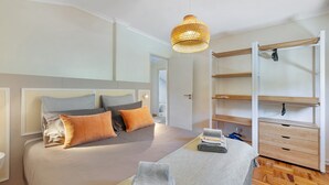 A modern bedroom with a bed, bedside tables, a hanging light fixture, and built-in shelving. - Lisbon Nearby. Surrounded by Nature. Beaches Always Close. (Trafaria)