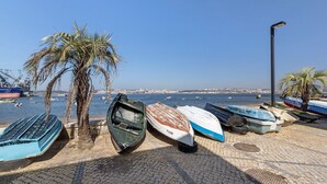 A coastal scene with boats, palm trees, and a clear sky. - Lisbon Nearby. Surrounded by Nature. Beaches Always Close. (Trafaria)