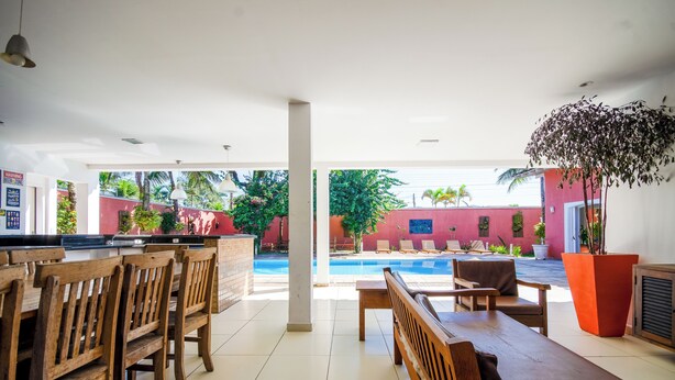 A spacious indoor area with a pool, wooden furniture, and a view of the outside. - Mansion for up to 28 people on Pernambuco Beach - 350m from the sea - air conditioning (Guarujá)