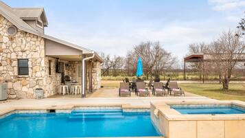 Ein Steinhaus mit Pool und Sitzgelegenheit im Freien.