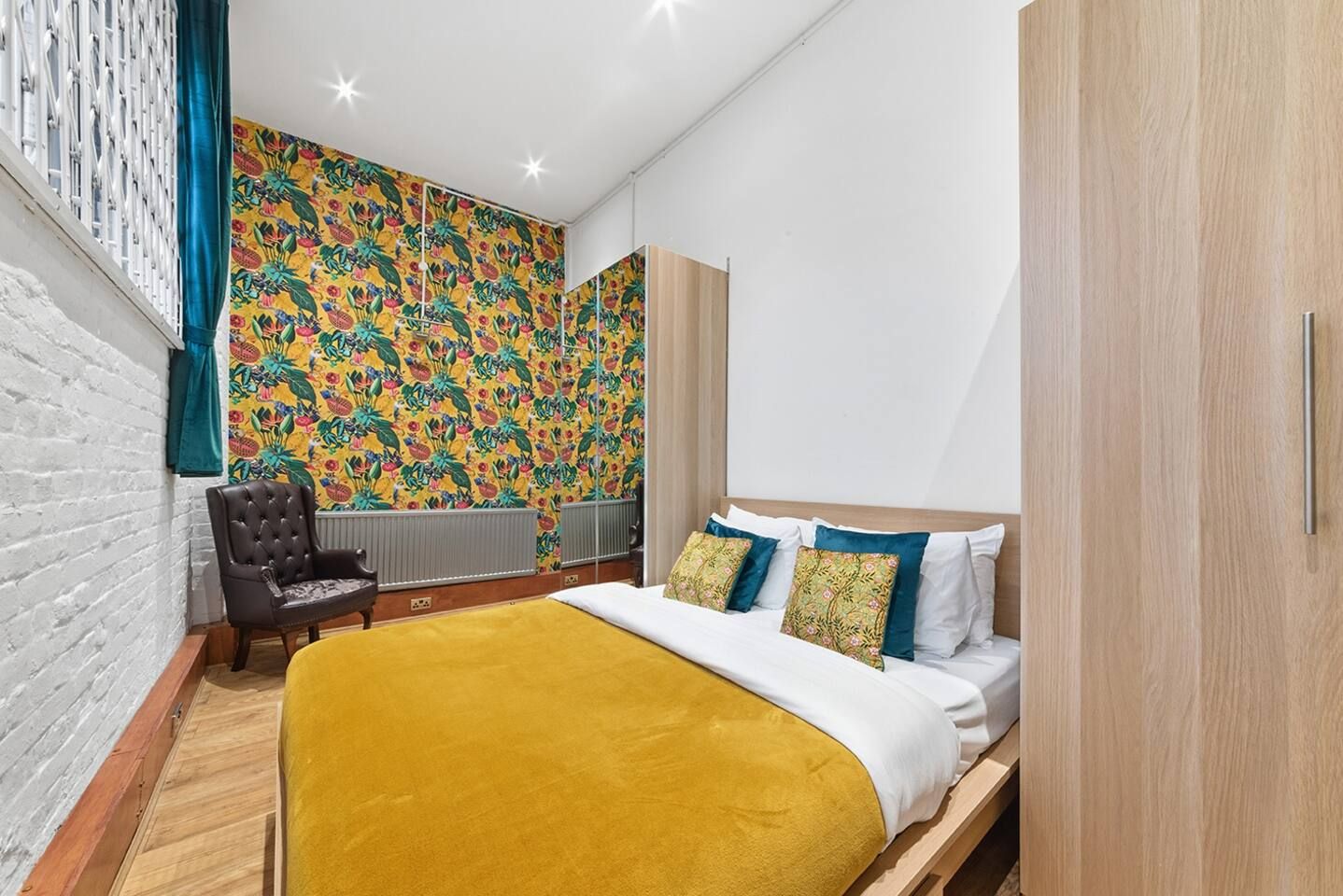 A bedroom with a bed, a chair, a wardrobe, and a radiator.