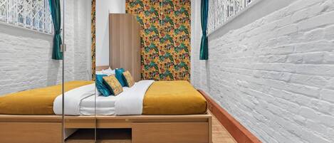 Une chambre moderne avec un lit en bois, une literie blanche et un papier peint à motifs floraux colorés.