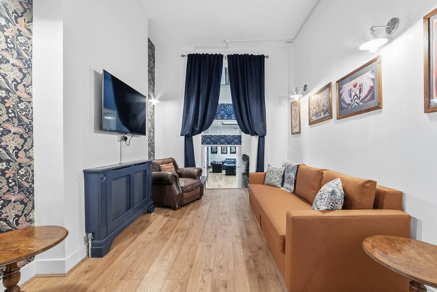 A living room with a sofa, a television, a cabinet, and a dining table.