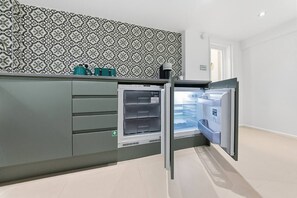 A modern kitchen with a built-in refrigerator, a patterned backsplash, and a door leading to another room. - Royal College St NW1, Camden Town, Camden Rd (London)