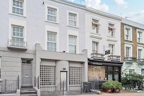 A row of white buildings with multiple windows, a storefront with a website address, and a gated entrance. - Royal College St NW1, Camden Town, Camden Rd (London)