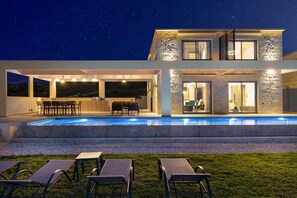 A modern house with a swimming pool, outdoor seating, and a stone facade. - Luxurious Villa Rocca Blanco 2 (Chania)
