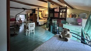 Un dormitorio con cama con dosel, una mesita con una silla, un osito de peluche y un aparador con espejo.