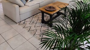 Un soggiorno con un divano bianco, un tavolino in legno e un quadro raffigurante un molo.