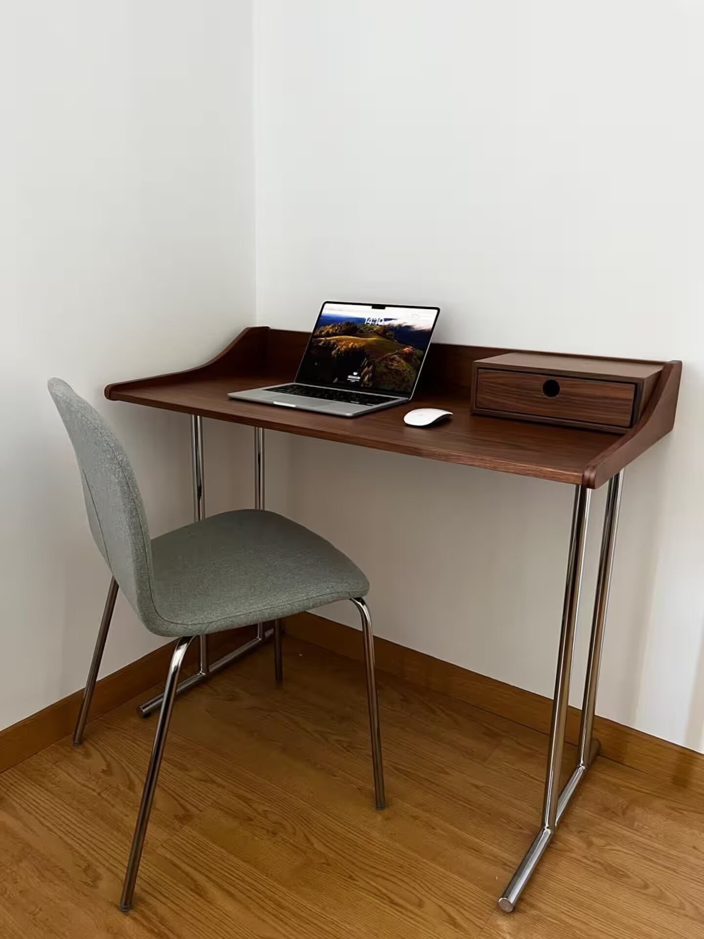 Ein Holztisch mit einem Laptop, einer Maus und einer Schublade.