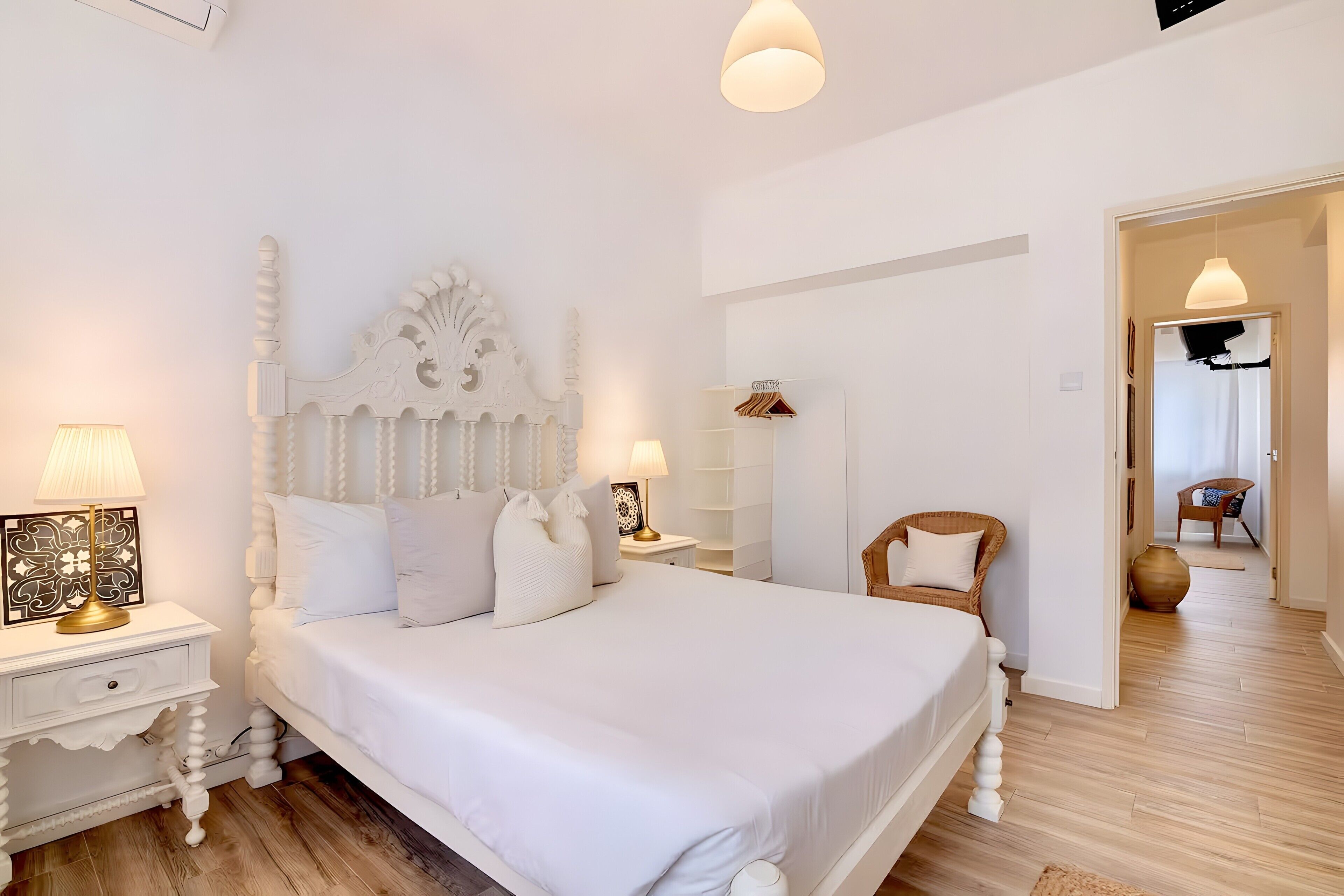 Ein Schlafzimmer mit einem großen Bett, zwei Nachttischen mit Lampen, einem Sessel und einem Kleiderschrank.