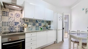 Una cocina moderna con baldosas estampadas, armarios blancos y un comedor con mesa y sillas.