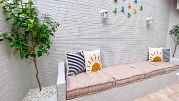 A seating area with a white brick wall, decorative wall lights, and a potted plant.