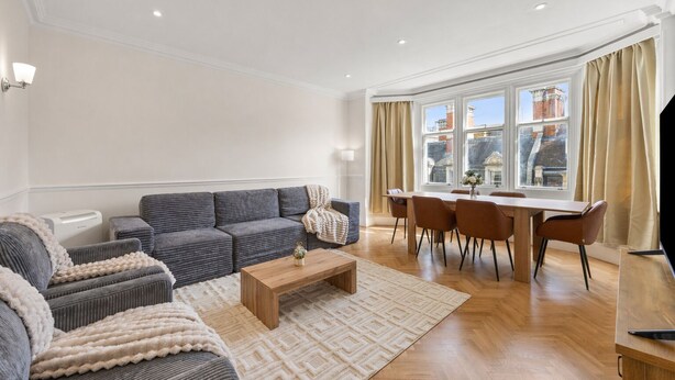 Een moderne woonkamer met een bank, een salontafel en een eethoek met stoelen en een tafel.