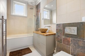 A bathroom with a bathtub, a shower, a vanity with a bowl sink, a mirror, and a window. - Luxury Mayfair 3BR Flat near Oxford St, full A/C (London)