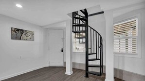 Een modern interieur met een wenteltrap, witte muren en een houten vloer.
